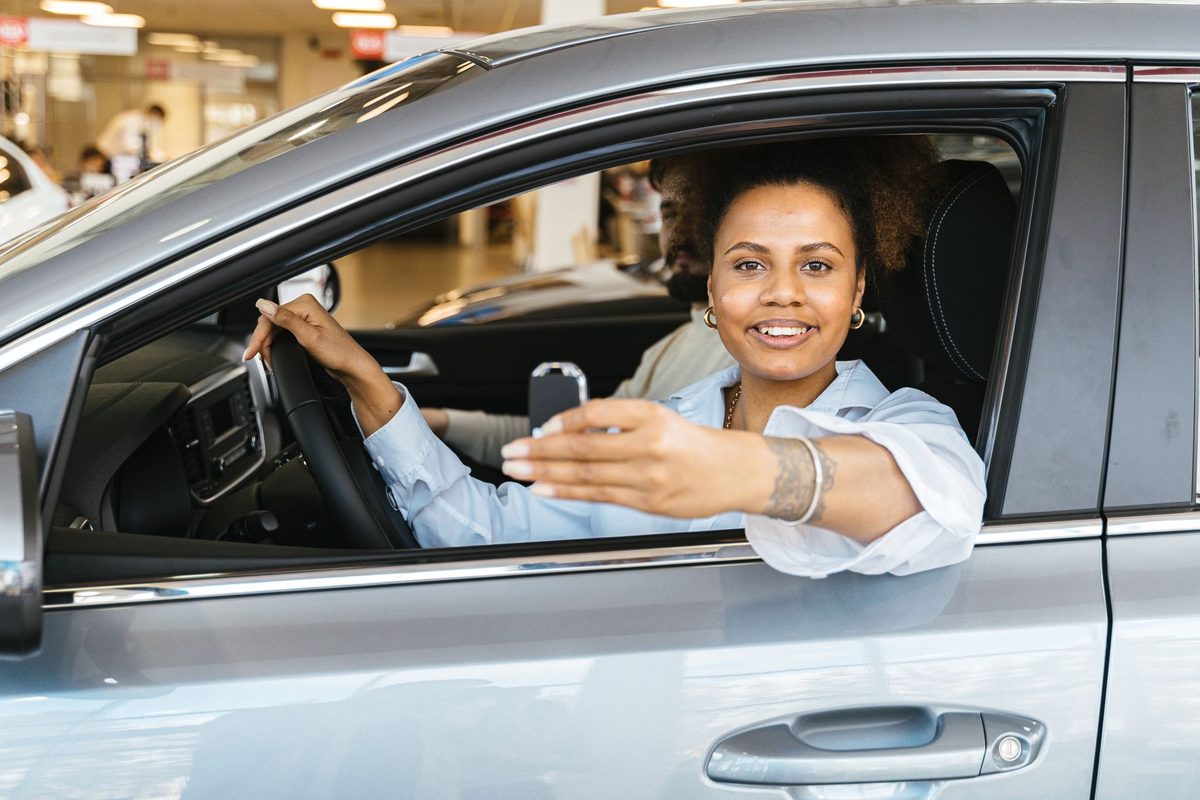 Mână care ține cheia de mașină la volan după promovarea examenului auto