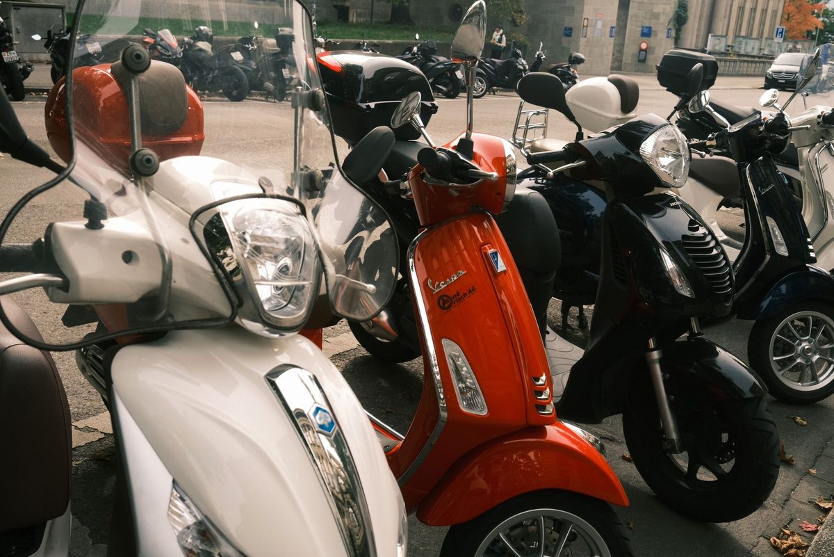 Scutere urbane parcate pe marginea unei străzi din oraș
