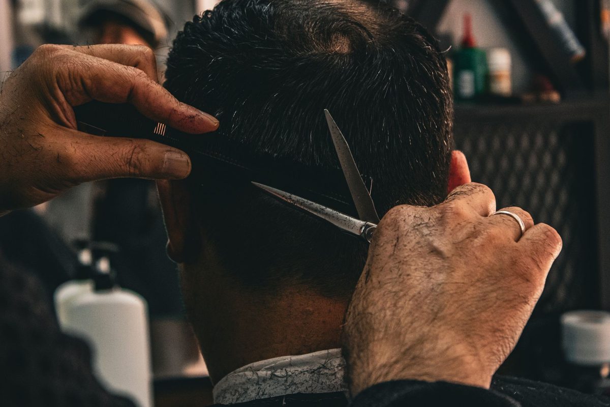 Frizer care tunde părul unui client într-un salon modern
