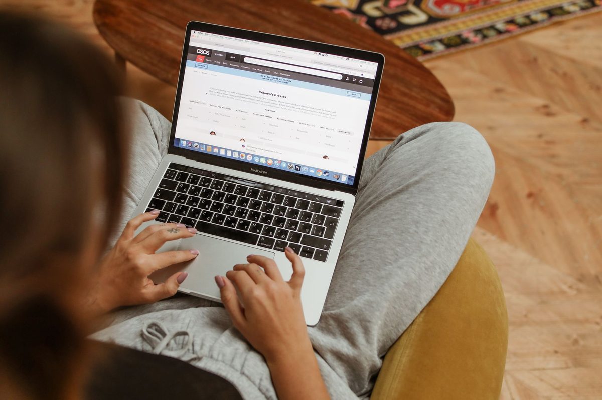 Persoană care citește un site pe laptop și se uită la un buton de pe pagină