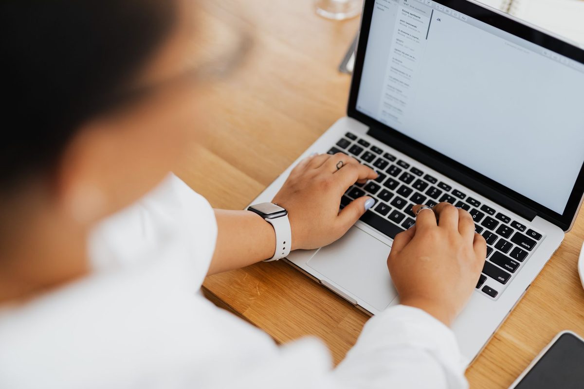 Persoana care scrie un e-mail de reamintire pe laptop