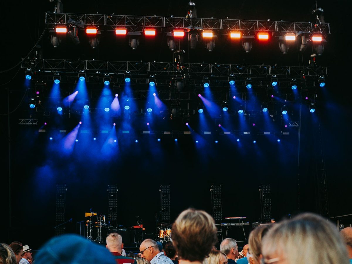 Mulțime la un concert, luminile scenei cad peste public