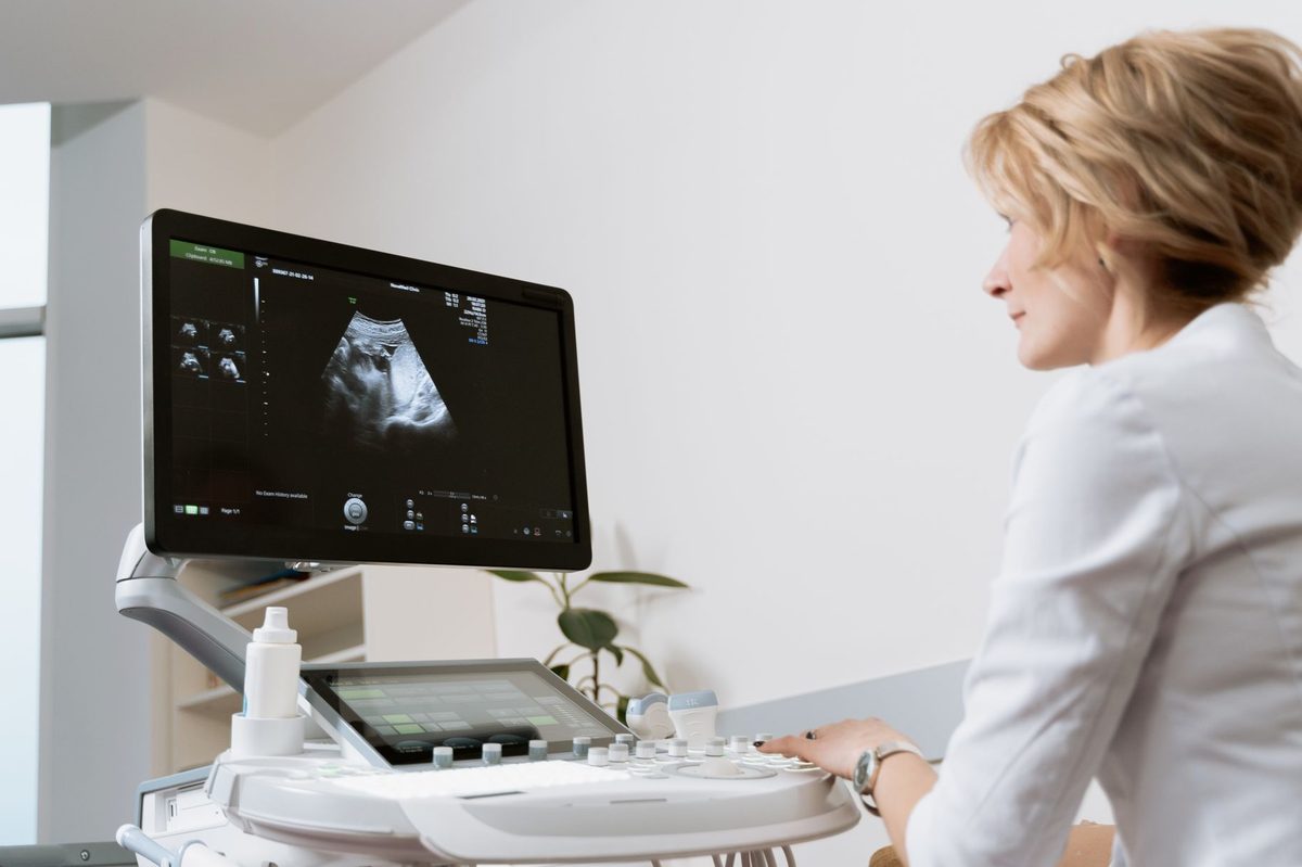 Medic care realizează o ecografie și urmărește imaginea pe monitor