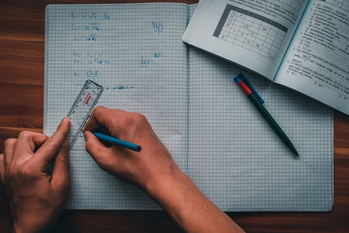 Elev care rezolvă o temă de geometrie cu echerul pe foaia milimetrică