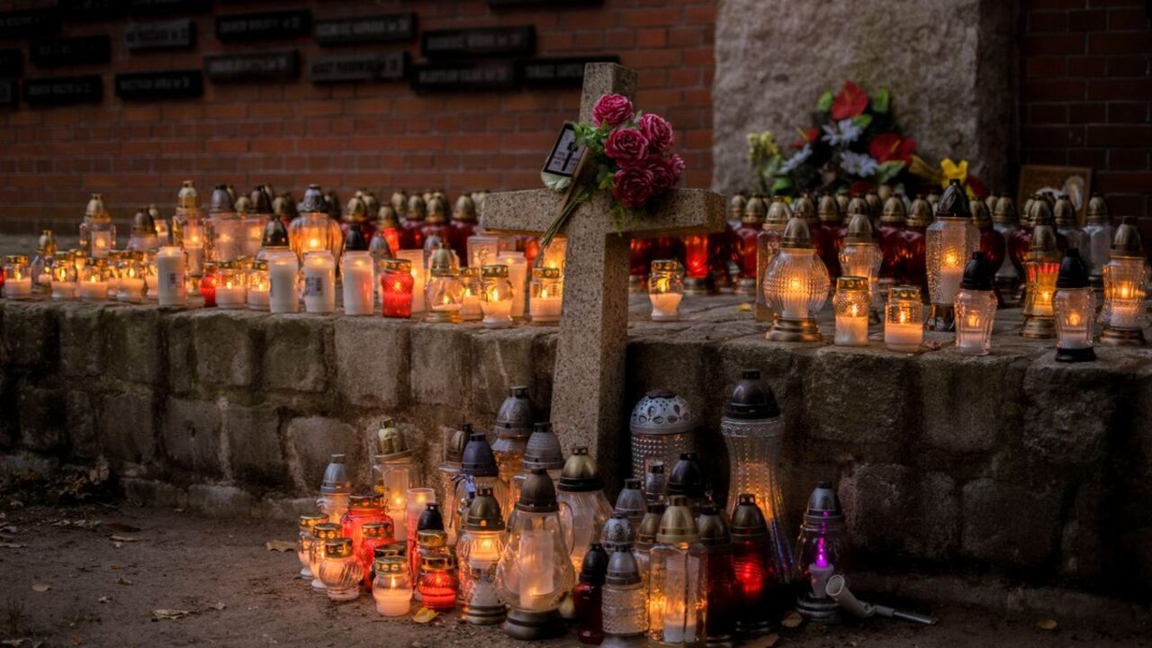 O cruce de piatră este înconjurată de numeroase candele aprinse într-un cimitir.