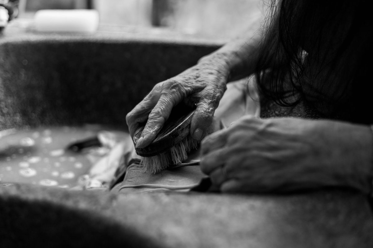 Mâini care spală rufe într-un lighean, imagine de vis casnic