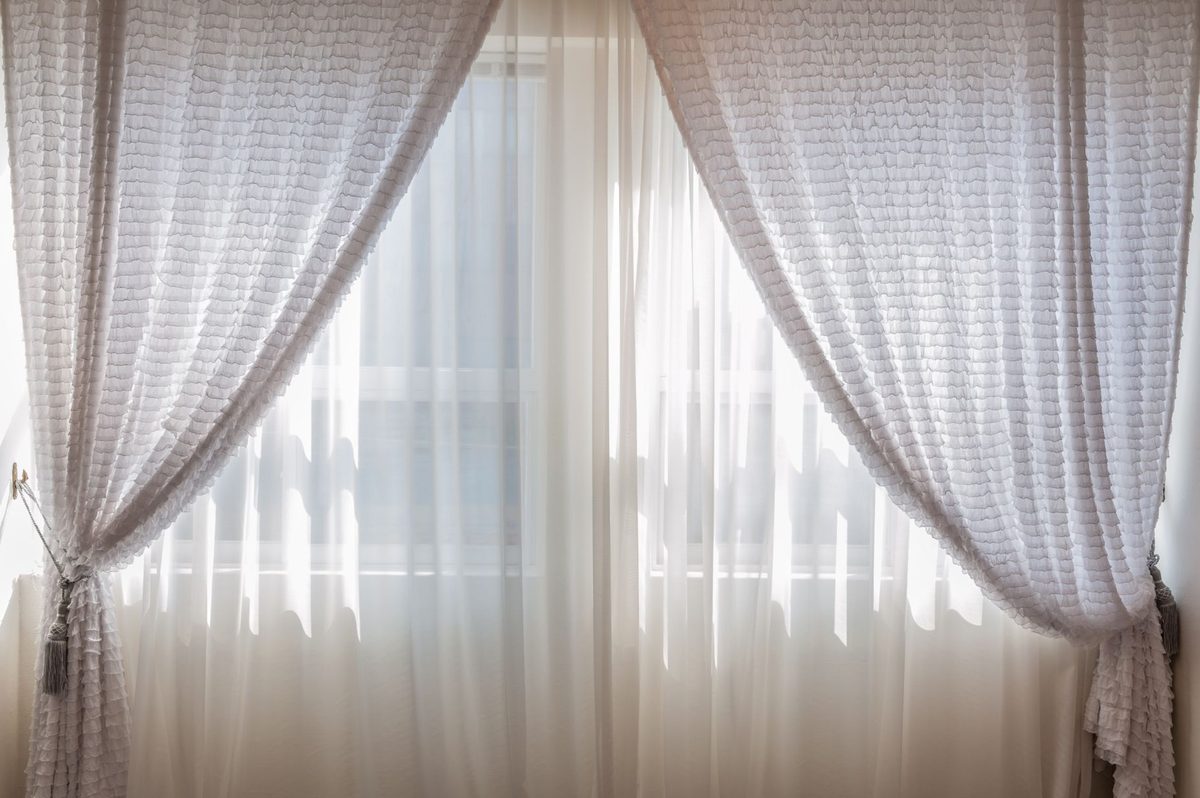 Perdea albă la fereastră, lumină blândă care trece prin pânză
