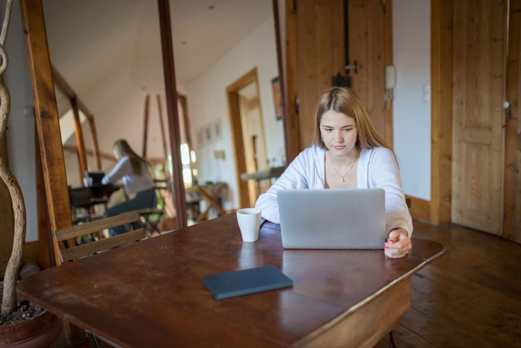 Persoană la laptop, la o masă din lemn