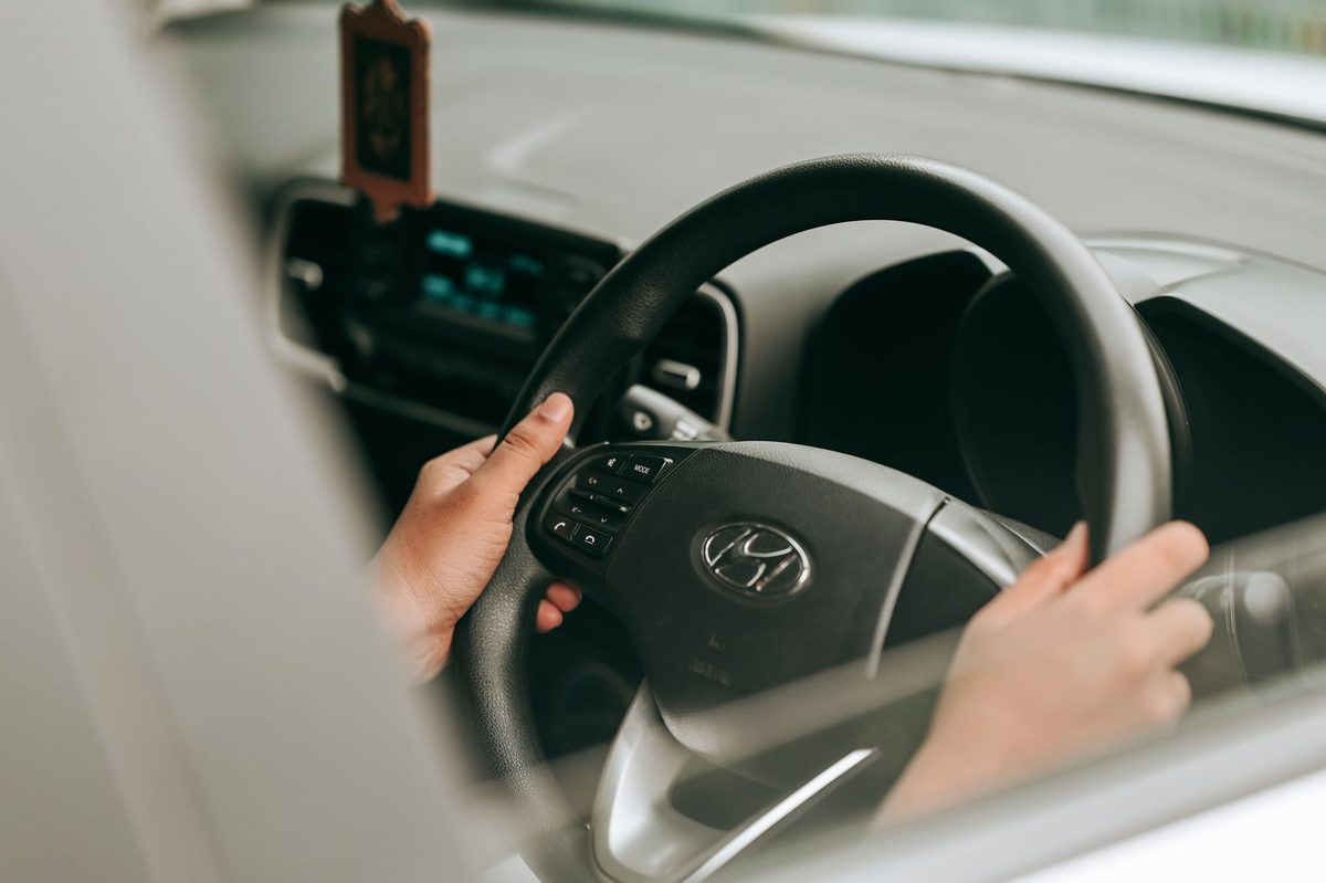 Mâini pe volan, văzute din interiorul mașinii, în visul că conduci fără permis
