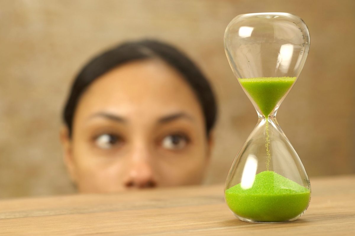 Clepsidră cu nisip care curge, simbolizând timpul trecător și natura efemeră a momentelor