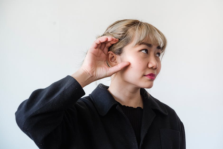 Femeie cu mâna la ureche ascultând atent, simbol al percepției auditive și superstiției