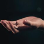 Ce Înseamnă Când Visezi Că Te Mănâncă Palma Stângă – Interpretare Completă Palmă stângă deschisă pe fundal întunecat reprezentând visele și misterul subconștientului