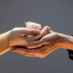 Bărbat și femeie atingându-și mâinile într-un gest romantic și intim