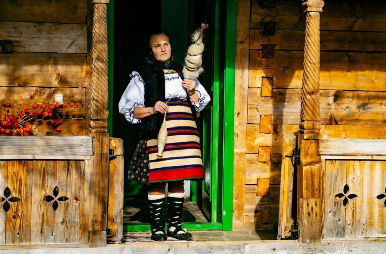 Mâini de bunică în vârstă împletite într-un cadru tradițional rural