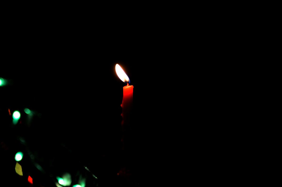 O lumânare aprinsă cu o lumină caldă, simbolizând liniștea și încheierea unei etape din viață