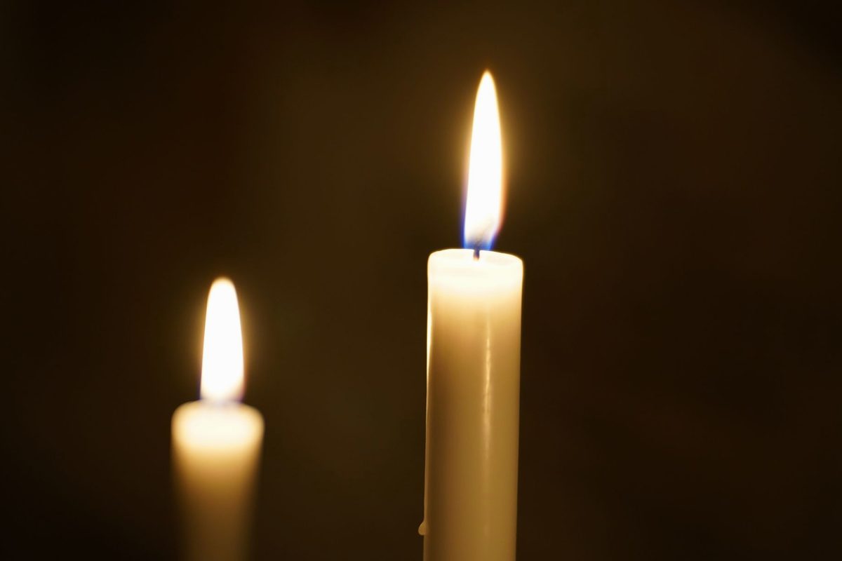 Două flăcări de lumânare arzând împreună pe un fundal întunecat