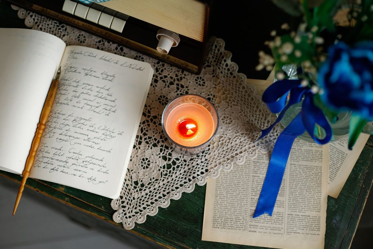 Femeie scriind gânduri și intenții într-un jurnal la lumina lumânării