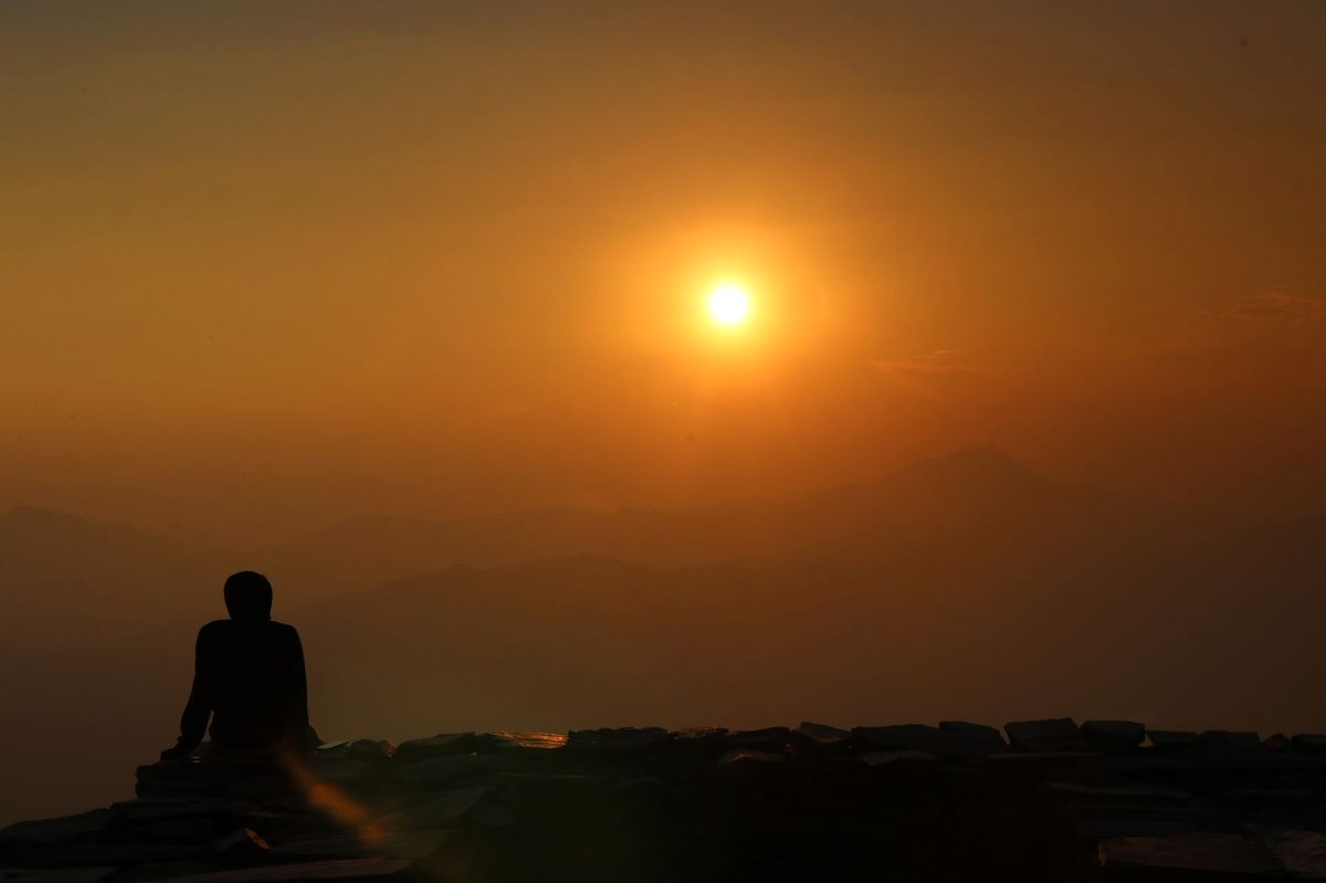 Silueta unei persoane meditând în liniște la răsăritul soarelui