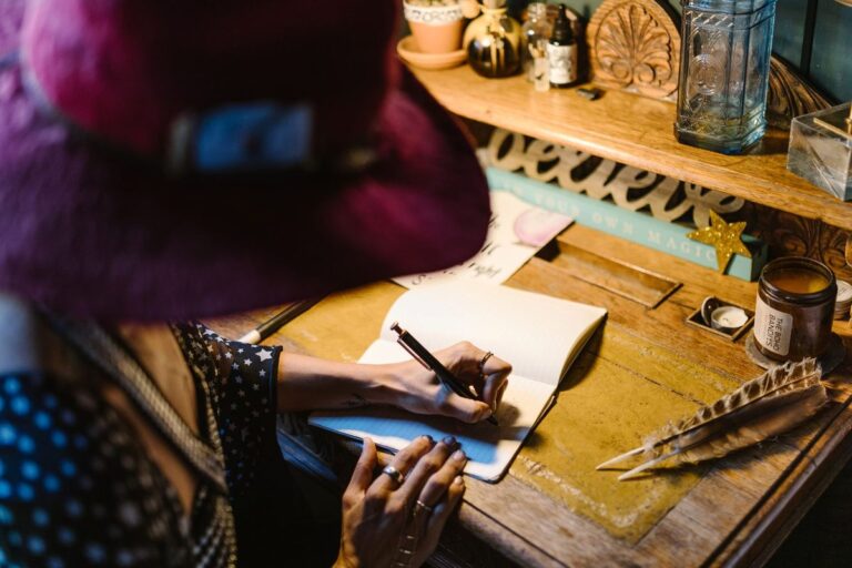 Femeie scriind gânduri și intenții într-un jurnal la lumina lumânării