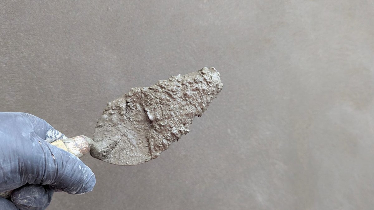 Mâini care lipesc un zid de lut într-un atelier rustic
