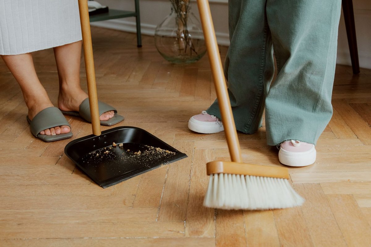 Mătură tradițională din nuiele măturând o podea rustică din lemn