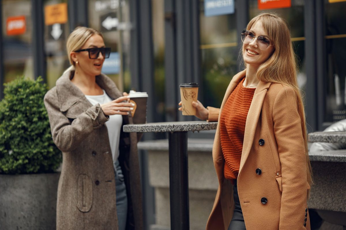 Două prietene discutând bucuroase la o cafea pe o terasă