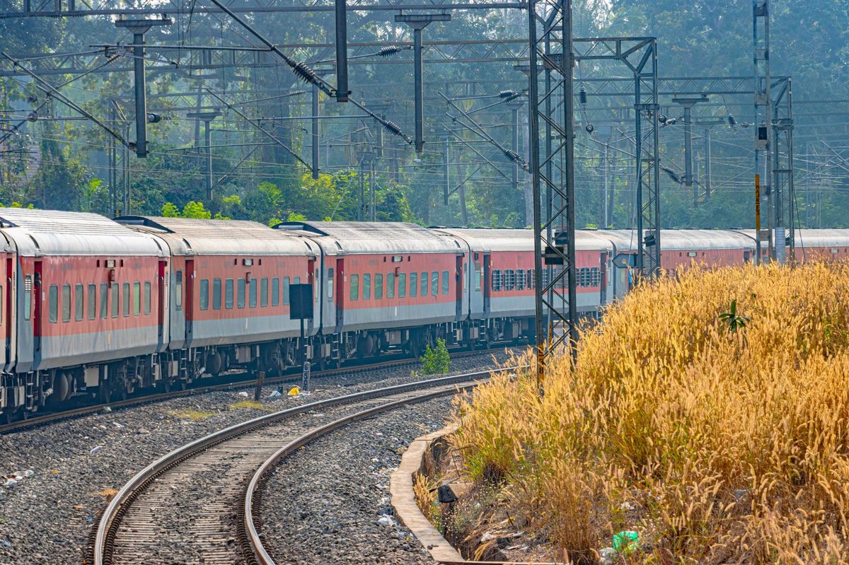 Tren de călători pe șine traversând peisajul rural