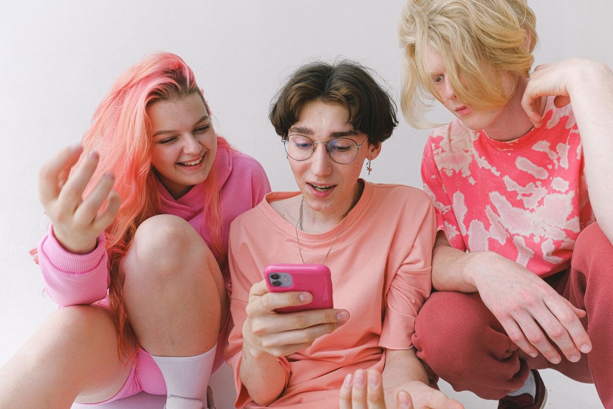 Adolescenți care râd uitându-se împreună la un telefon