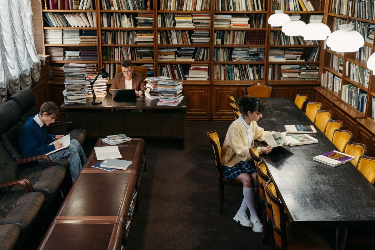 Bibliotecă școlară luminoasă cu mese de studiu și caiete deschise.