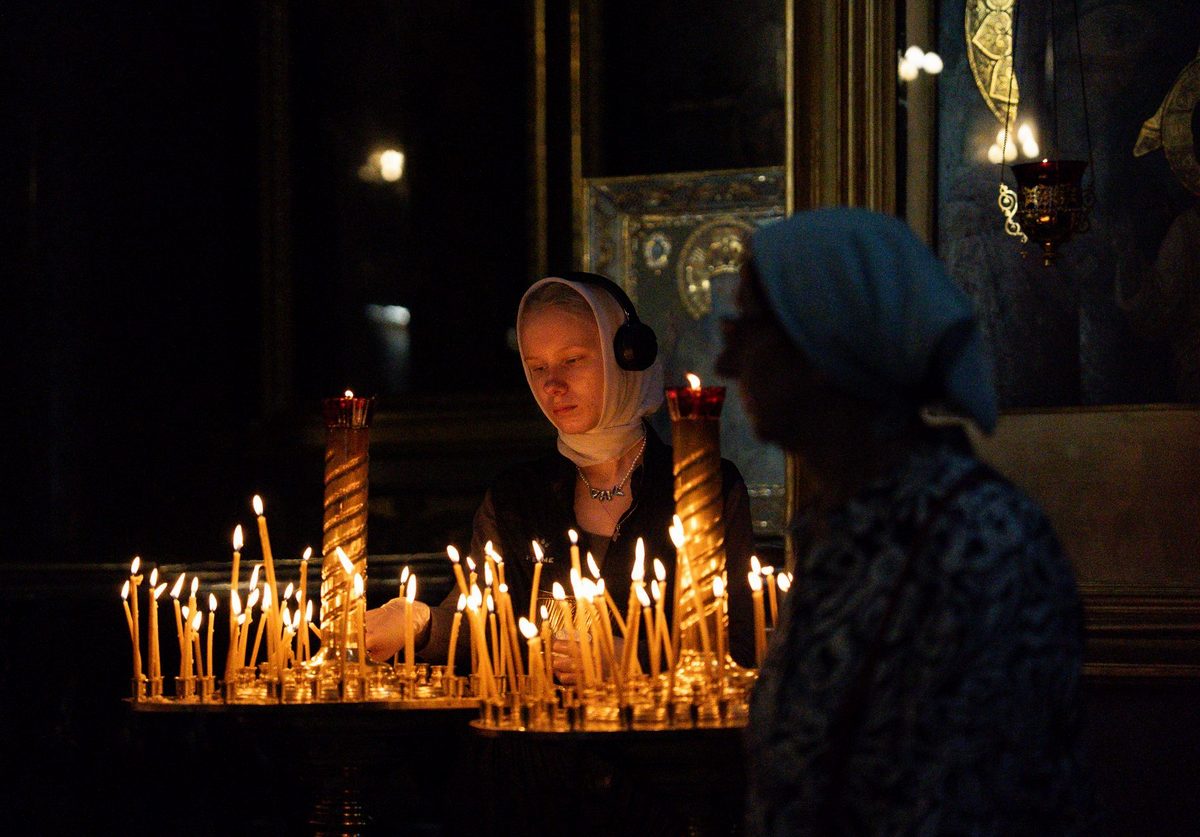 Lumânări aprinse de credincioși într-o biserică ortodoxă