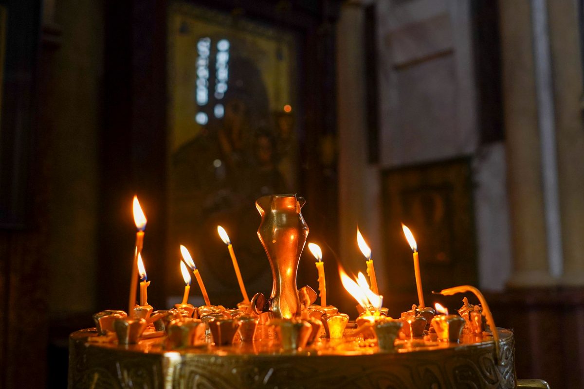 Familie aprinzând lumânări într-o biserică ortodoxă